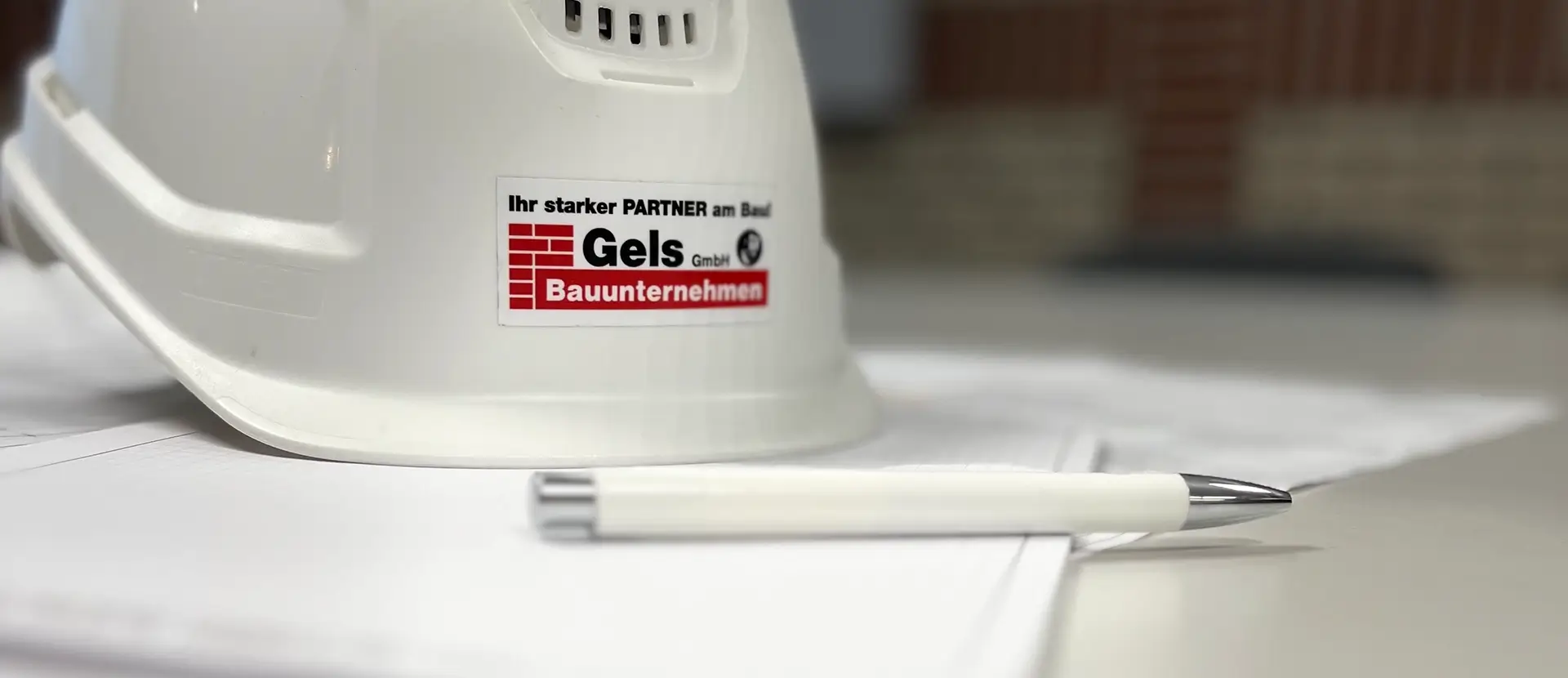 Gels Bauhelm liegt auf Papier mit Kugelschreiber daneben